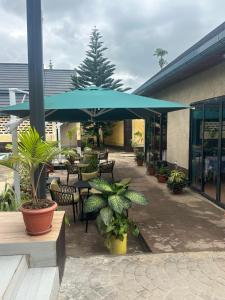 a patio with tables and chairs and a blue umbrella at La Mariette Hôtel & Resort in Kisantu