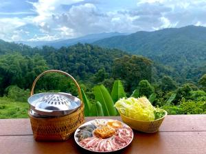 a table with two plates of food and a basket of food at Thammachart The Nature in Ban Kai Noi