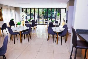 a dining room with tables and chairs and windows at The Hide on Aston-Sandton in Johannesburg