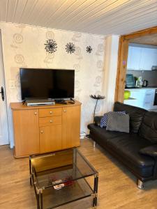 a living room with a black couch and a tv at Appartement Daria in Prémanon