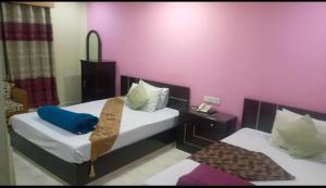 two beds in a room with pink walls at Stylus guest house in Sreemangal