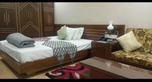 a bedroom with a bed and a couch and a table at Stylus guest house in Sreemangal
