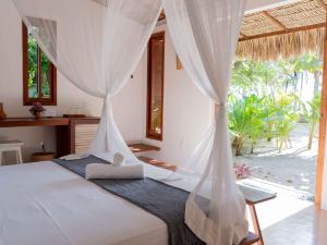 a bedroom with a bed with white drapes at Muita Paz in Atins