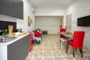 a kitchen and living room with a table and red chairs at Plaza Suites in Piazza Armerina +29 photos