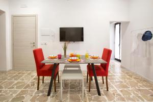 a dining room with a table and red chairs at Plaza Suites in Piazza Armerina