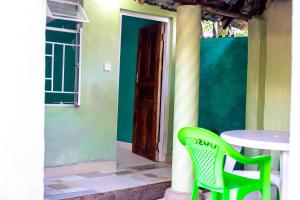 a table and two green chairs in front of a house at Mount Mulanje Stopover in Peremwe