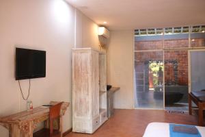 a living room with a tv and a wooden cabinet at The Secreet Garden Hotel in Denpasar