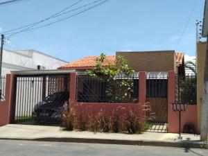 a fence in front of a house with a car at Casa em local tranquilo - Bairro Recanto dos Pássaros in Cuiabá