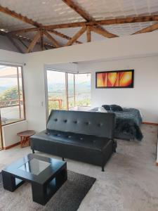 a living room with a black leather couch and a bed at Glamping Orosierra in Chinchiná
