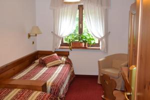 a bedroom with a bed and a chair and a window at Hotel Bosco Verde in Mareson