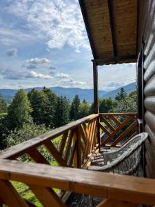 a wooden balcony with a view of the mountains at Sosnova hilka in Mykulychyn