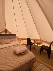 a bedroom with a bed and chairs in a tent at Desert Romance Retreat in Muntarib