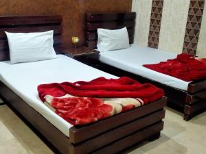 two beds in a room with red sheets at Hotel Decent Lodge in Multan +40 photos