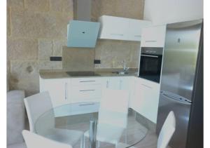 a kitchen with white cabinets and a glass table at Piso con vistas a 30m playa ALOJAMIENTOS VACAY in Bueu