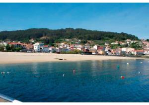 a view of a beach with a town in the background at Piso con vistas a 30m playa ALOJAMIENTOS VACAY in Bueu