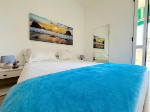a white bedroom with a large bed with blue sheets at Casa Mia - Baia Verde in Baia Verde