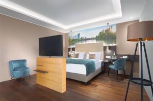 a bedroom with a bed and a desk and a tv at Mercure Frankfurt Offenbach in Offenbach