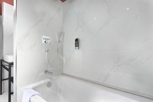 a bathroom with a tub and a shower with a mirror at Mercure Frankfurt Offenbach in Offenbach