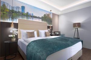 a bedroom with a large bed with a green blanket at Mercure Frankfurt Offenbach in Offenbach +7 photos