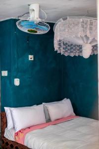 a bed in a room with a blue wall and a fan at Mount Mulanje Stopover in Peremwe