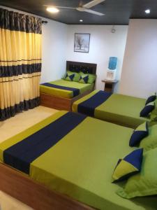 two beds in a room with green and blue at Moonlight Resort in Anuradhapura
