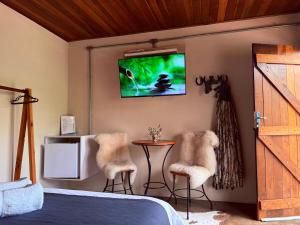 a bedroom with a bed and a tv on the wall at Refúgio Horse in Santo Antônio do Pinhal