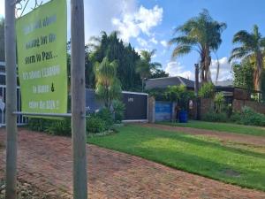 a sign in front of a house with palm trees at SomethingElz@Grace in Pretoria