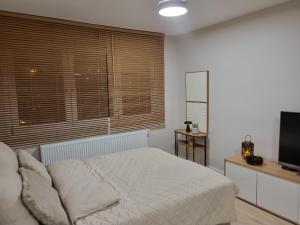 a white bedroom with a bed and a television at Apartament Sobótka in Sobótka