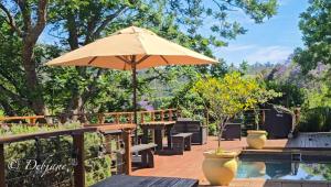 eine Terrasse mit Sonnenschirm und Stühlen sowie ein Pool in der Unterkunft Cavalo Guesthouse & Equestrian Estate in Drummond