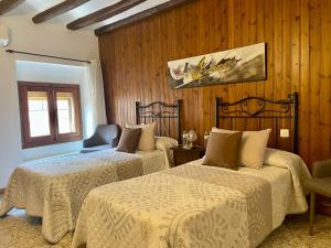 a hotel room with two beds and a chair at Hostal i Apartaments Populetus in Poboleda