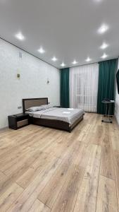 a large bedroom with a bed and a wooden floor at ЖК Central Park in Aktobe