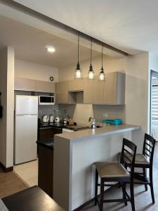 a kitchen with a counter and chairs and a refrigerator at Paseo Recoleta in Cochabamba