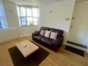 a living room with a leather couch and a coffee table at The Mews & Studio in Ivybridge +2 photos