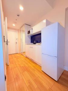 a white refrigerator in a kitchen with a wooden floor at ASKO aprtament beach batumi in Batumi