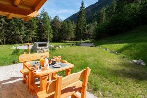 a picnic table with two wooden chairs in a field at Baita Valon La Piciola in Stenico