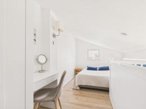 a white bedroom with a bed and a chair at Maison proche Golf plage et piscine à Pornic in Pornic
