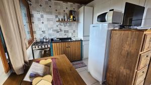 a kitchen with a white refrigerator and a table at Casa Kitnet Loft Bidu House in Imbituba