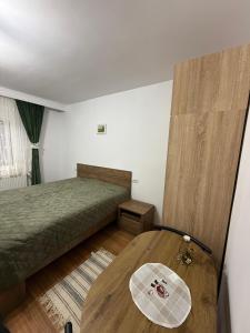 a bedroom with a bed and a wooden table at Casa Bunicii in Târgu Neamț