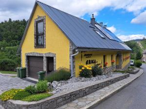 a yellow house with a black roof on a street at Soba Erika in Fužine