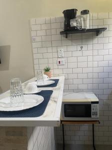 a kitchen counter with two plates and a microwave at Studio Home Residence in Jacareí