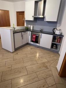 a kitchen with white cabinets and a wooden floor at Ferienwohnung Schwarzwald - Nähe der Schweiz in Hüfingen
