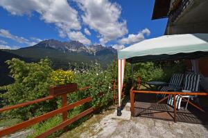 a table and chairs under an umbrella on a balcony with mountains at CasaInesAldo in Candide