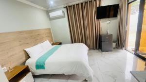 a bedroom with a bed and a flat screen tv at Mjee's Guest House in Ulundi