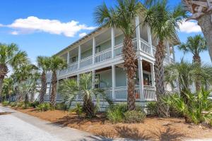 a large white house with palm trees in front of it at Sea La Vie , Walk Everywhere in Rosemary Beach