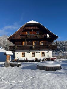 a large building in the snow in front at Ferienwohnung Lahnerhof in Arriach
