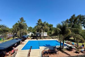 a large swimming pool with tables and chairs and palm trees at Aires Del Delta in Tigre