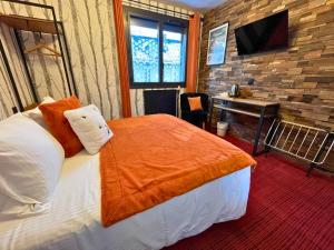 a bedroom with a bed and a desk with a television at Hôtel La Rencluse in Luchon
