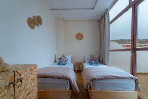 two beds in a room with a large window at Roots Surf House - Anza in Agadir
