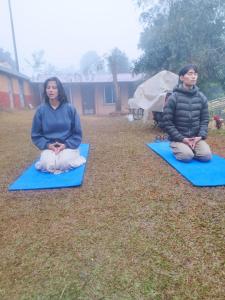 two women sitting on mats in the grass at Mountain View Eco Farm in Rānīpauwa