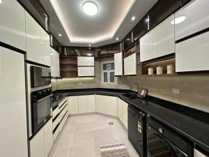 a large kitchen with white cabinets and black appliances at Super Luxury Private Complex Apt In New Cairo in New cairo